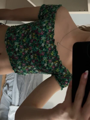 Grön blommig croppad topp - Superfin kort sommartopp med grönblommigt mönster. Kan bäras på axlarna eller off-shoulder. Jag tror att den är från H&M men är inte helt säker då lappen är bortklippt