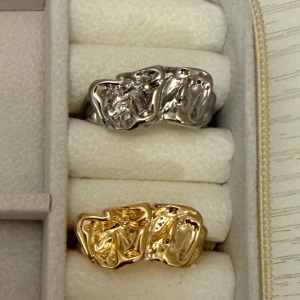 Chunky ringar i guld och silver - Två chunky ringar med organisk, skulpterad yta i guld- och silverfärg. Rå och modern design som sticker ut och ger en cool vibe. Perfekt för dig som gillar statement-smycken och vill addera lite edge till din stil.( styck pris)