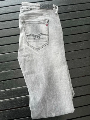 Grå slim fit jeans från Replay - Snygga grå slim fit jeans från Replay med klassisk femficksdesig. Jeansen har en svart Replay-lapp bak i midjan och detaljerade sömmar på bakfickan. Tillverkade i mjukt denimtyg som ger en bekväm känsla. Modell Rosé Storlek W29 L32 pris går att diskutera 