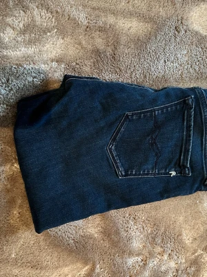 Mörkblå skinny jeans från Replay - Snygga mörkblå skinny jeans från Replay med klassisk femficksdesign och subtila slitningar. Jeansen har en modern passform och är tillverkade i stretchigt denim som ger en bekväm känsla. Perfekt för dig som gillar stilrena och trendiga jeans.