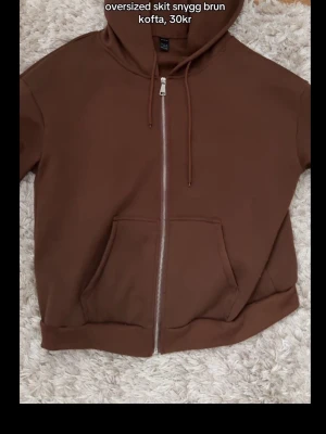 Brun oversized hoodie från SHEIN - Säljer en oversized brun hoodie från SHEIN med dragkedja framtill, stor ficka och justerbar huva. Hoodien är gjord i mjukt material och har ribbade muddar vid ärmslut och nederkant. Perfekt för en chill och avslappnad stil.