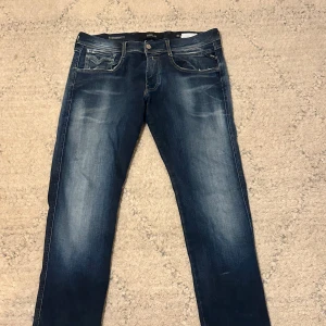 Mörkblå jeans med slitningar - Säljer ett par mörkblå jeans med snygga slitningar och tvättade detaljer. Klassisk femficksmodell med raka ben och kontrastsömmar. Jeansen har en cool streetwear-vibe och passar perfekt till en avslappnad stil. Storlek w33 l32 men passar w32