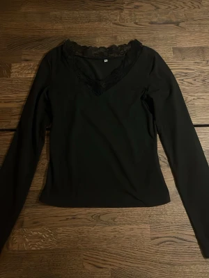 Svart långärmad topp med spets - Svart topp med spetsdetaljer, i nyskick. Säljes då den inte längre används. Perfekt för alla tillfällen! Hör av dig för mer information.❤️