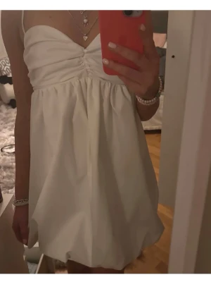 Vit klänning zara - Söt vit kort klänning med v-ringad byst och tunna axelband. Klänningen har en lätt puffig kjol och rynkade detaljer vid bysten. Perfekt för sommarens alla tillfällen och studenten!💕 den har en dragkedja på sidan. Säljer då den tyvärr är för liten för mig!🥰