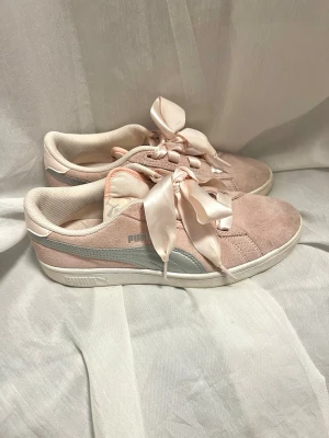Puma rosa sneakers med sidenband - Säljer ett par supergulliga rosa sneakers från Puma med unika satinband som snörning. Skorna har en vit sula och en silverfärgad rand på sidan. Lägg gärna ett bud!💕