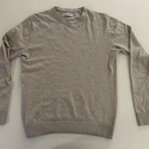 Beige tröja från Jack & Jones - En stilren beige tröja från Jack & Jones i mjukt material. Tröjan har rund halsringning, långa ärmar och ribbade muddar vid ärmslut och nederkant. Perfekt för en avslappnad och snygg look.