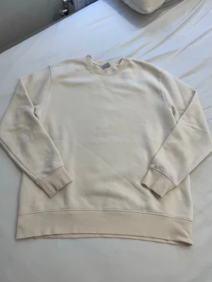 Vit sweatshirt från Zara - Klassisk vit sweatshirt från Zara i storlek M. Tröjan har rund halsringning, ribbade muddar vid ärmslut och nederkant samt en avslappnad passform. Perfekt basplagg för en clean och enkel stil.