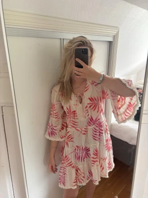 Vit och rosa blommig kortklänning - Superfin kortklänning i vitt med rosa och röda blommiga mönster. Aldrig använd 🌺🐚💐