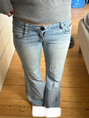 Ljusblå bootcut jeans  - Säljer ett par ljusblå bootcut jeans från Musketeer med låg midja och klassiska fem fickor. Byxorna har ett litet hål på det vänstra låret som inte påverkar helheten!!🧘🏼‍♀️🩵