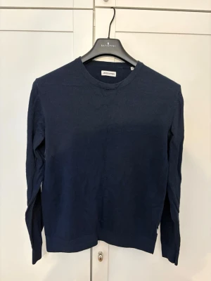 Mörkblå stickad tröja Jack & Jones - Mörkblå stickad tröja från Jack & Jones med rund halsringning och långa ärmar. Tröjan har en enkel och stilren design, perfekt att matcha med jeans eller chinos. Materialet känns mjukt och bekvämt mot huden.