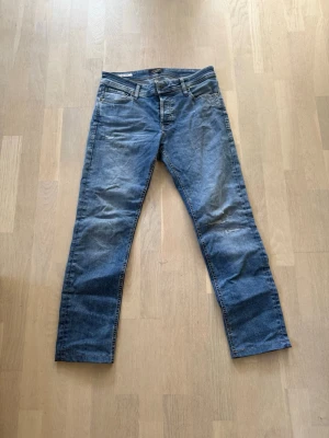 Blå slim fit jeans från Jack & Jones - Slim fit jeans från Jack & Jones i klassisk blå denim med lätt slitna detaljer och femficksmodell. Modellen heter Glenn och har en smal passform med normal midja. Perfekta för en avslappnad och trendig look. Sydda till min längd är 176 cm 69kg 