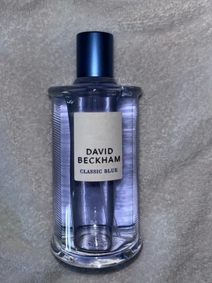 David Beckham Classic Blue parfym 100ml - Fräsch parfym från David Beckham, Classic Blue, i en stilren glasflaska med blått lock. Flaskan rymmer 100 ml Eau de Toilette och har en modern, transparent design med blå toner. Perfekt för dig som gillar sportiga och eleganta dofter.