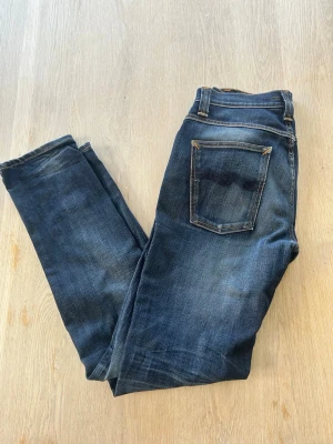 Nudie Grim Tim Jeans - Säljer ett par Nudie Grim Tim Jeans i storlek W32 L32. Har lagat fickan en gång hos Nudie affären i Göteborg (syns på bilderna).  32/32