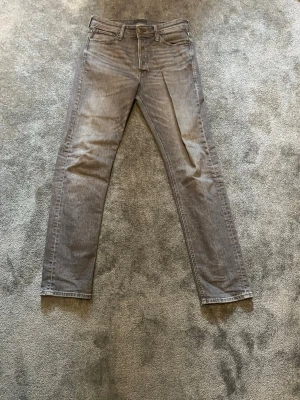 Gråa relaxed fit jeans från Jack & Jones - Snygga gråa relaxed fit jeans från Jack & Jones med klassisk femficksmodell och dragkedjegylf. Jeansen har raka ben och är tillverkade i mjukt denimtyg som ger en skön känsla. Perfekta för en avslappnad och trendig look.