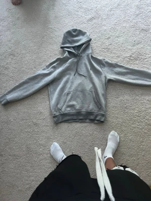 Grå hoodie från Polo Ralph Lauren - Snygg grå hoodie från Polo Ralph Lauren med klassisk huva och dragsko. Tröjan har en känguruficka framtill och den ikoniska lilla broderade loggan på bröstet. Tillverkad i mjukt bomullsmaterial som är perfekt för chill dagar.
