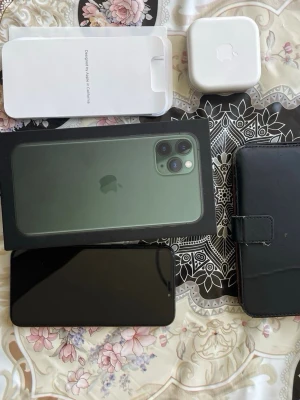 iPhone 11 Pro Max grön 256GB - Säljer en iPhone 11 Pro Max i snygg mörkgrön färg med 256GB lagring. Telefonen har en stor OLED-skärm, tre kameror på baksidan och elegant glasbaksida. Medföljer originalkartong, laddare och svart plånboksfodral. Perfekt för dig som vill ha en kraftfull och stilren mobil.