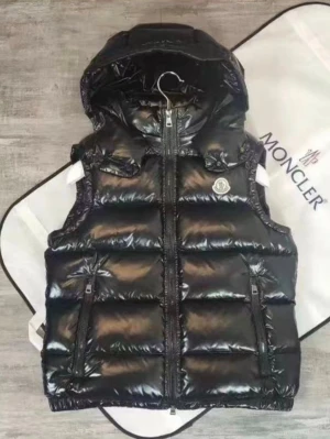 Svart dunväst från Moncler - Snygg svart dunväst från Moncler med glansig finish och huva. Västen har två dragkedjefickor framtill, Moncler-logga på bröstet och quiltad design. Perfekt för lager-på-lager och streetstyle.
