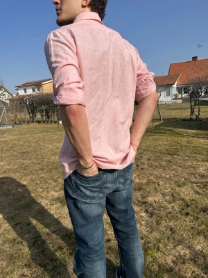 Ljusrosa skjorta med knappar - Säljer en ljusrosa skjorta i bomull med klassisk krage och knappstängning framtill. Skjortan har en bröstficka och långa ärmar som kan vikas upp. Perfekt för en avslappnad men ändå stilren look. Säljer för den är för stor 
