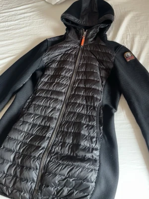 Svart parajumprr jacka dam  - Säljer min Parajumpers-jacka som jag köpte för några år sedan. Jag använder den tyvärr inte längre, så den förtjänar att komma till någon som faktiskt får nytta av den.  Jackan är äkta. Jag kan försöka leta fram kvittot vid behov. Men det finns även Scan koden som visar att den är äkta.  Skick: • Fickan är lite trasig men går att fixa. • Det finns en mindre skada, men den syns inte särskilt mycket.  Annars är jackan fortfarande fin och varm. Hör gärna av dig vid intresse eller om du har frågor!