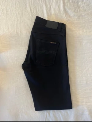 Svarta jeans från Nudie Jeans - Snygga svarta jeans från Nudie Jeans. Jeansen har diskret logga på bakfickan och är tillverkade i ett stretchigt bomullsmaterial för skön passform. Säljes pågrund av fel storlek, oanvända. Kom gärna med frågor. Priset är något diskutabelt vid snabb affär 