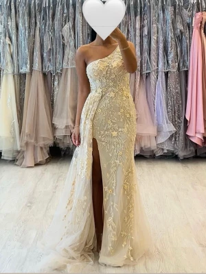 Balklänning / festklänning champagne storlek 34 - Elegant balklänning i champagnefärg i storlek 34. Enaxlad design med fina spets- och broderidetaljer samt hög slits. Väldigt fin till bal, fest eller bröllop. I mycket bra skick. Köpt för 4000kr. 