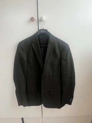 Mörkgrön linnékostym från H&M Edition  - Stilren mörkgrön kostym från H&M Edition i lätt linnematerial. Klassisk passform med två framfickor med lock, bröstficka och två knappar vid ärmslut. Perfekt för en dressad look med modern touch. Använd endast 2 gånger. Skick 9/10. Nypris 2500 kr 