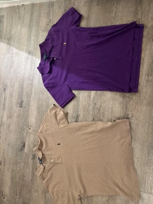 Beige pikétröja från Polo Ralph Lauren - Klassisk beige pikétröja från Polo Ralph Lauren samt en lilla pikétröja från polo med liten broderad logga på bröstet. Tröjan har krage, korta ärmar och knappar vid halsen den beiga är storlek S och den lilla är 14-16 barn . Båda ingår hör av dig vid frågor.
