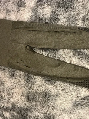 Olivgröna seamless träningstights - Snygga olivgröna seamless träningstights med hög midja och meshdetaljer på benen. Tightsen har ventilerande partier längs sidorna och bak, vilket ger extra komfort under träningspasset. Tillverkade i stretchigt funktionsmaterial som sitter skönt mot kroppen.