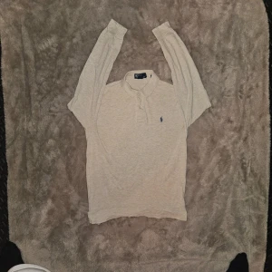 Vintage Polo Ralph Lauren Långärmad Polo (Beige) 🔥 - Beige långärmad Polo Ralph Lauren med marinblå pony 🐎 Pit to pit: 51-54 cm Längd: 68-71 cm Skick: bra – fint skick (se bilder). Två pyttesmå hål vid taggen och muddarna på båda ärmarna har gått upp lite (inget som syns vid användning och inget seriöst alls). Husdjurs- & rökfritt hem. Snabb frakt från Sverige! DM för mer bilder 💨