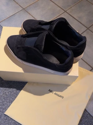 Mörkblå  Axel Arigato 360 laceless sneakers  - Stilrena mörkblå 360 laceless sneakers från Axel Arigato med ovandel i mocka och elastiska band över vristen. Skorna har vit sula och minimalistisk design som passar till det mesta. Levereras med originalkartong och dustbag. Skick 8,5/10. Hör av dig vid frågor eller vid önskan av fler bilder😊 allt og tillkommer!