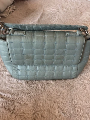 Blå handväska - Säljer en blå handväska jag har fått av min kusin som jag vill minnas var oanvänd. Använd fåtal gånger av mig där jag kan se lite defekter på väskan men den är fortfarande funktionell. Dragkedja och magnetknappar. 