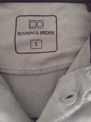 Olivgrön pikétröja Bogeys & Birdies - Snygg olivgrön pikétröja från Bogeys & Birdies i storlek S. Tröjan har klassisk krage, korta ärmar och knappslå framtill. Tillverkad i ett mjukt och funktionellt material som passar perfekt till sport och golf.