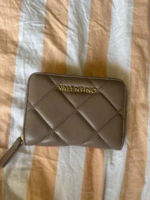 Brun quiltad plånbok från Valentino - Snygg brun plånbok från Valentino med quiltat mönster och guldfärgad logga framtill. Helt ny, aldrig använd. 