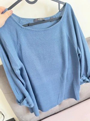 Blå stickad tröja från Esprit - Snygg blå stickad tröja från Esprit med rund halsringning och långa ärmar. Ärmarna har en cool detalj med knut vid ärmsluten. Perfekt till jeans eller kjol för en avslappnad look.