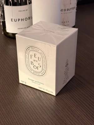 Diptyque Feu de Bois doftljus 190g - Säljer ett - Diptyque Feu de Bois doftljus i originalförpackning. Ljusets förpackning är vit med klassisk Diptyque-logga och text i svart. Innehåller 190g doftljus som sprider en elegant och träig doft. Perfekt för att skapa mysig stämning hemma.