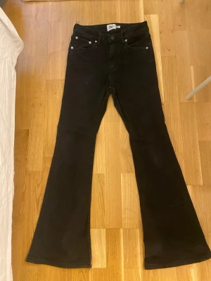 Svarta utsvängda jeans från lager 157 - Svarta jeans med utsvängda ben från lager 157. Jeansen är stretchiga och sköna. Lite skador på jeansen längst ner som man ser på bild 2.