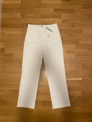 Vita raka linnebyxor med fickor - Snygga vita linnebyxor med raka ben och diskreta sidofickor. Byxorna har en klassisk midja och stängs med dragkedja. Perfekta för en fräsch och stilren look. Materialet är lätt och luftigt linne, vilket gör dem sköna att bära under varma dagar.