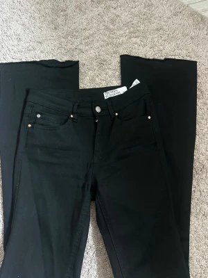Svarta bootcut jeans från Vero Moda - Snygga svarta bootcut jeans från Vero Moda. Jeansen har en medelhög midja och är utsvängda i benen. De är uppsprättade längst ned.