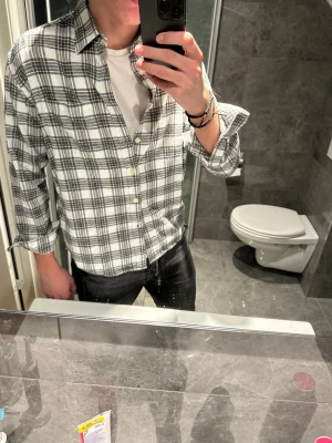 Vit och svart rutig skjorta - Säljer en vit och svart rutig skjorta. Flanellskjorta är riktigt snygg och passar perfekt nu till våren. Skjortan är i riktigt bra skick och har inga defekter. Jag på bilden är 188cm och bär storlek S vilket är ganska litet. Hör av er vid fler frågor:)