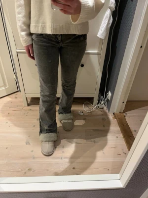 Grå bootcut jeans med tvättad look - Säljer ett par grå bootcut jeans med tvättad effekt och klassisk femficksmodell. Jeansen har normal midja och lätt utsvängda ben. Perfekta för dig som gillar en avslappnad men ändå trendig stil.