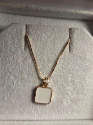 Elegant guldhalsband med pärlor - Snyggt halsband i guldfärg med en tunn kedja och dekorativa pärlor. Perfekt för att ge din outfit en lyxig touch. Kedjan har en klassisk design och pärlorna är vita och glänsande.