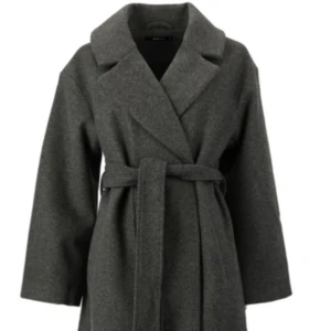 Grå kappa med bälte - Säljer en stilren grå kappa med snörning i midjan. Perfekt för höst och vinter! Den har en krage och långa ärmar, vilket gör den både varm och elegant