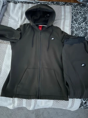 Nike dress - Säljer en svart zip hoodie från Nike med huva och dragsnören. Tillverkad i mjukt material som känns skönt mot huden. Perfekt för en avslappnad och sportig stil. Kan även passa någon med storlek S. Köpt för 900 kr. Tveka inte på att höra av er 