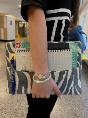 Zebramönstrad datorväska - Snygg datorväska med zebramönster i svart och vitt. Väskan har en mjuk textil utsida och praktiska ytterfickor för block, pennor och andra småsaker. Perfekt för att bära laptop och skolmaterial på ett stilrent sätt.