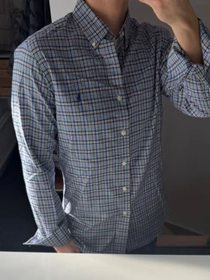 Rutig skjorta från Polo Ralph Lauren - Säljer en klassisk rutig skjorta från Polo Ralph Lauren med button-down krage och broderad logga på bröstet. Skjortan har långärmad design, knappar framtill och är tillverkad i mjuk bomull. Perfekt för dig som gillar stilrena och tidlösa plagg. Nypris ca 1400kr 🙌🏼