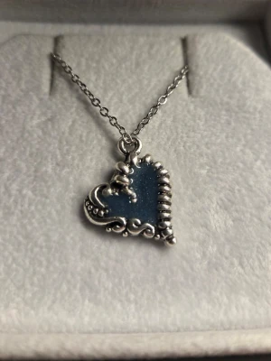 Halsband med självlysande hjärta - Unikt halsband med en kedja i rostfritt stål och ett hjärtformat hänge som lyser blått i mörkret. Hänget har en stilren design och ger en cool effekt när det lyser upp. Perfekt accessoar för dig som vill sticka ut lite extra. Kedjan är 45 cm. Vanligt dagsljus räcker för att hänget ska ändra färg och börja lysa i mörker. 