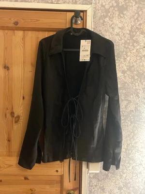 Svart satintopp med snörning - Svart satin topp med snörning från Zara. Helt oanvänd med prislapp på. Skriv vid frågor!💗
