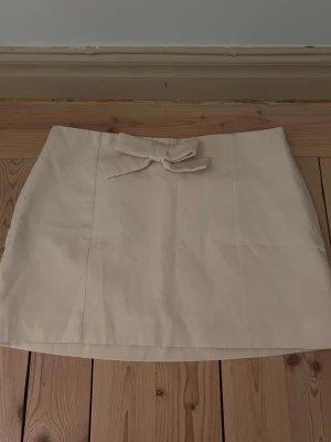 Beige kortkjol med rosett - Jag säljer nu denna super söta kjol från Zara som tyvärr aldrig kommit till användning. Köptes förra sommaren. Drajkedja på sidan och en super söt rosett.💕