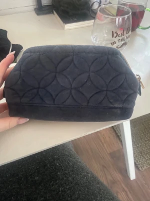Mörkblå quiltad necessär - Snygg mörkblå necessär med quiltat mönster i sammetstyg. Väskan har en mjuk, boxig form och stängs med dragkedja upptill. Perfekt för att förvara smink eller småprylar. Enkel och stilren design utan synligt märke.