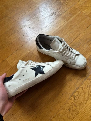 Golden goose skor - Riktigt fräscha golden goose i riktigt bra skick. Storlek 45. Säljer då de va för små tyvärr. Inga defekter på utsidan men finns ett litet hål på insida hälen men inget jag har märkt av vid användning men därav priset. Bara att höra av sig!🙌
